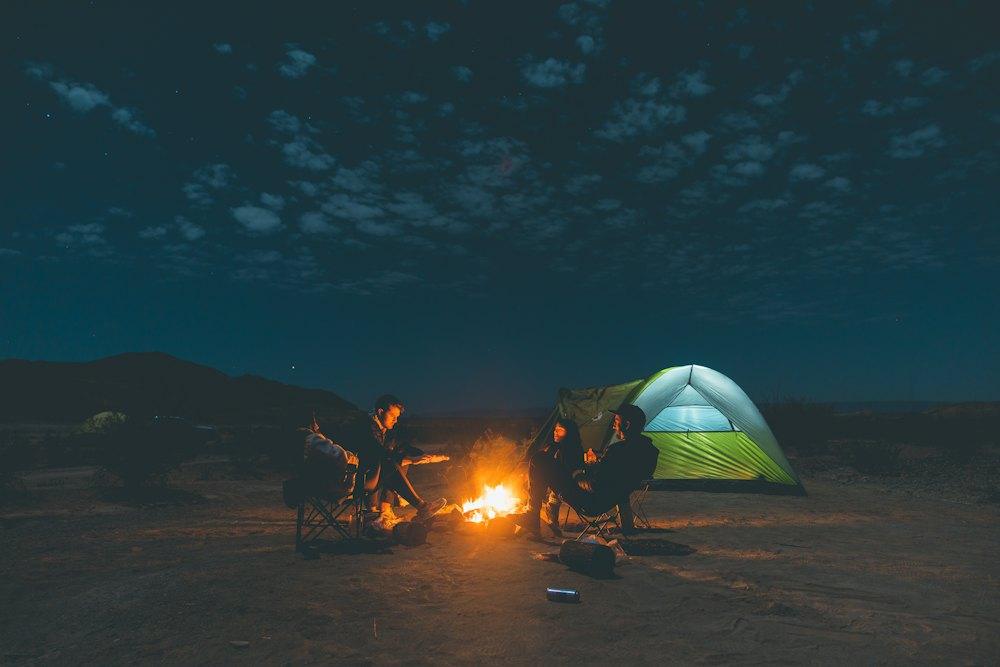 Riders around a campfire next to a tent at night