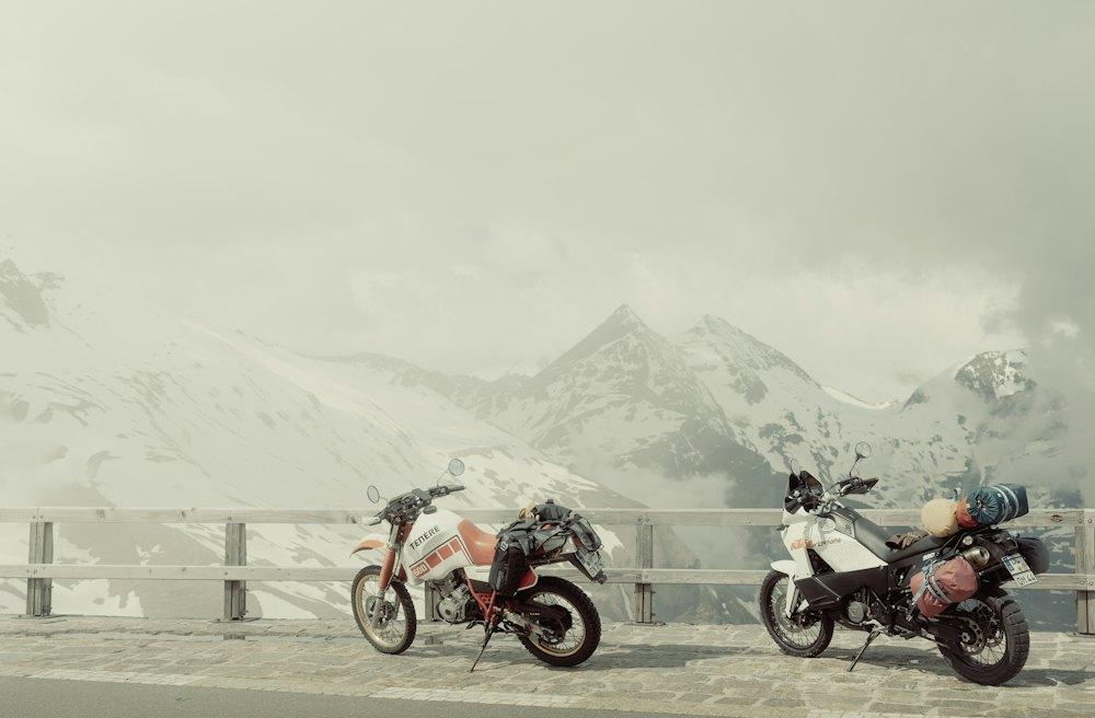 Two bikes in fog below snowy peaks