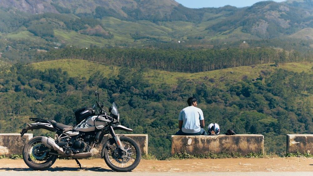 Rider resting beside a bike above green hills