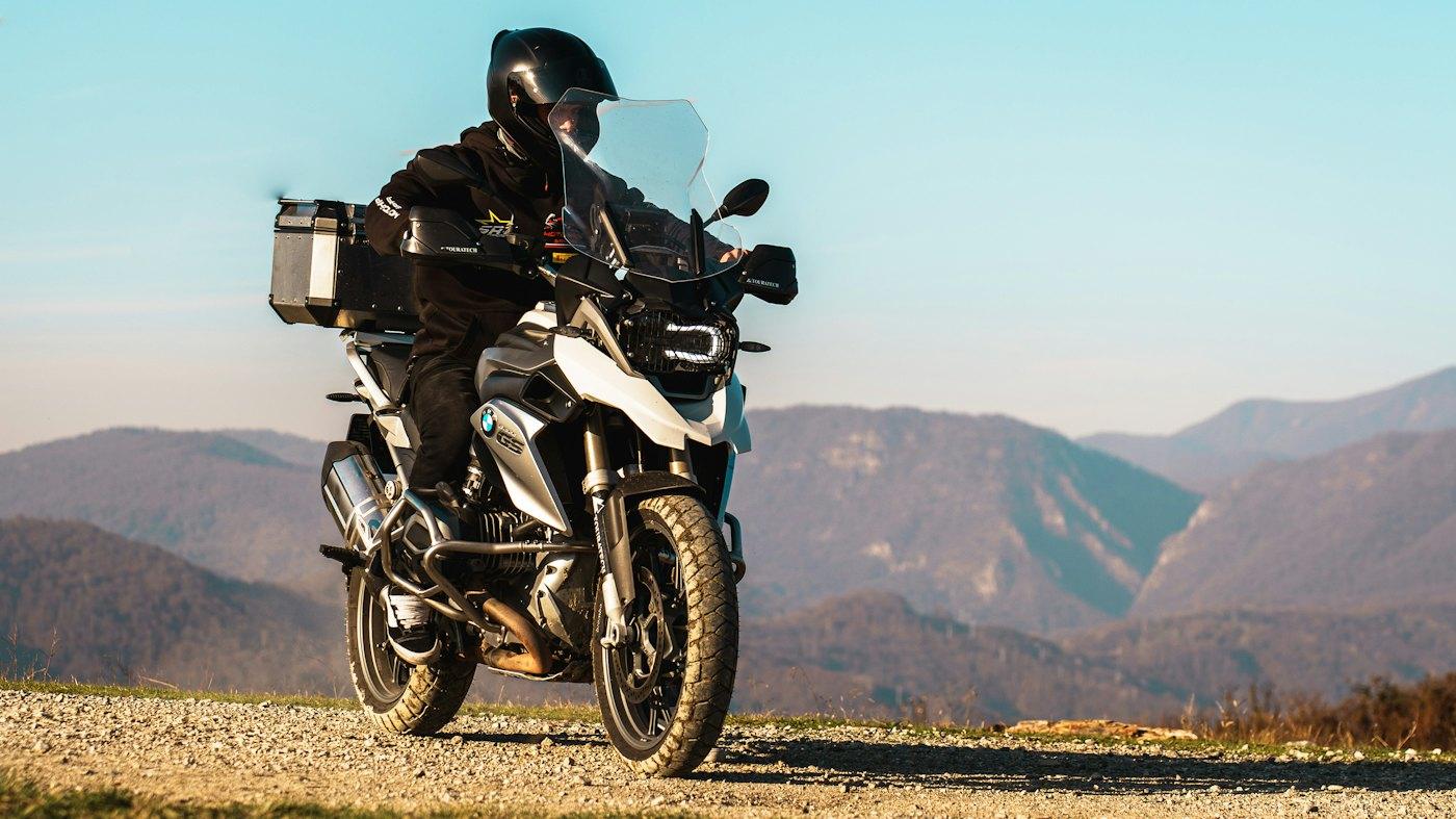 Rider on a loaded adventure bike on a mountain gravel road at golden hour