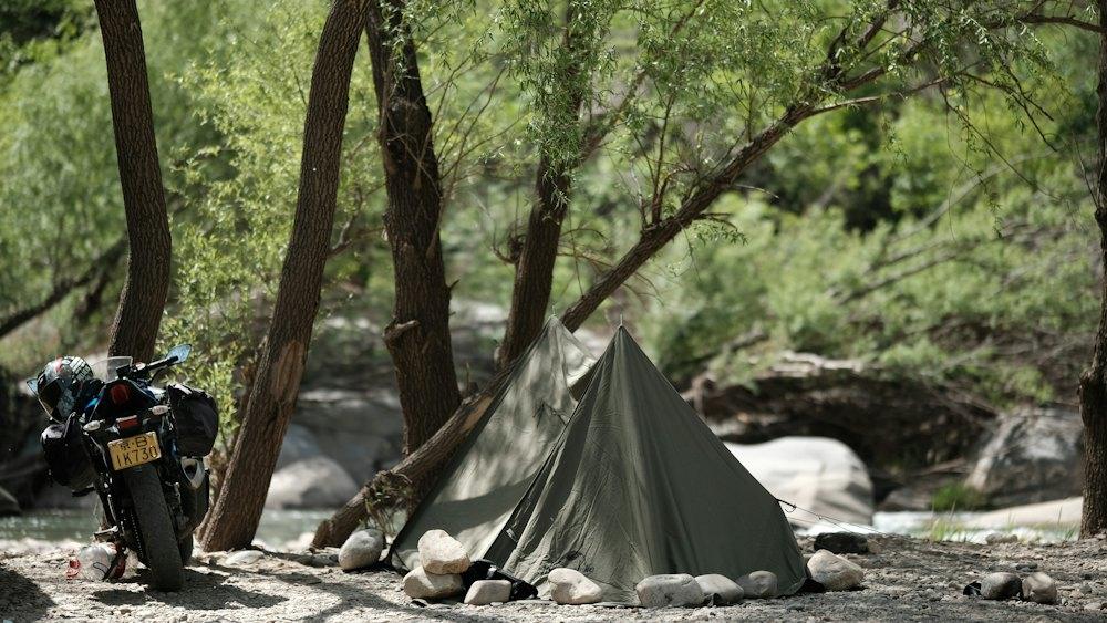 Tent and motorcycle by a rocky stream in the forest